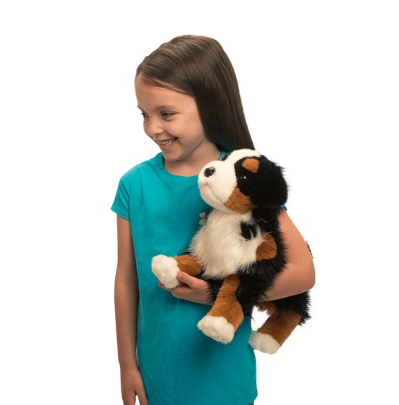 Girl smiling and holding plush Bernese Mountain Dog Trevor with soft tri-color fur and loving expression