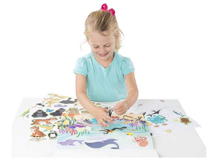 Young girl playing with Sticker Pad Habitats, placing reusable vinyl animal and ocean stickers on colorful scenes.