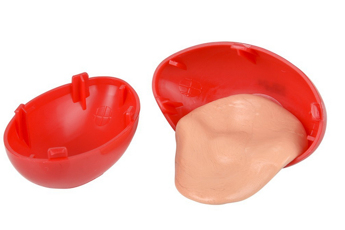 Silly Putty beige putty stretched out of red plastic egg container on white background.