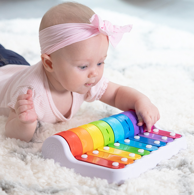 Baby playing colorful keys on the Rock N Roller Piano, exploring early musical learning with curiosity and joy.
