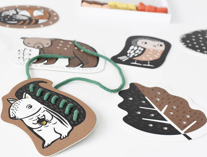 Woodland Lacing Cards featuring hand-illustrated animals with green lacing thread on thick, durable boards for motor skill development.