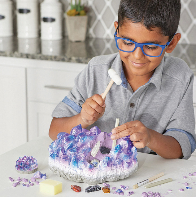 Child using chisels to uncover gemstones in the Dig It Up Giant Gem Discovery educational toy.