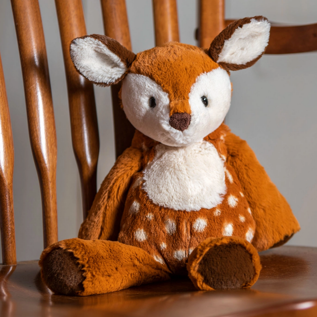 Marshmallow Fawn plush toy sitting on wooden chair, soft fabric with embroidered details and durable plastic eyes.