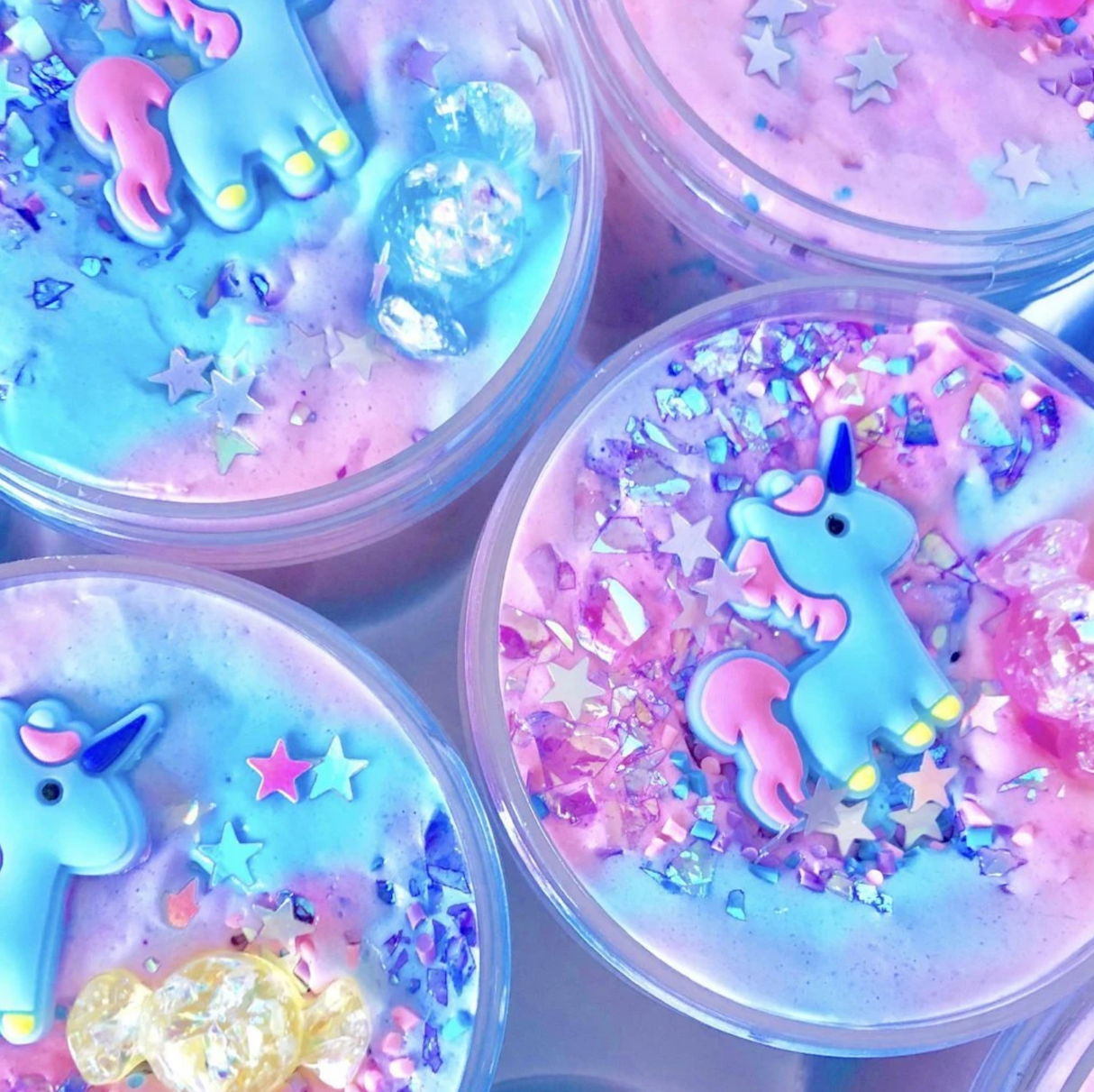 Close-up of colorful Don't Feed the Unicorns Butter Slime with unicorn charms, holographic stars, and sprinkle decorations.