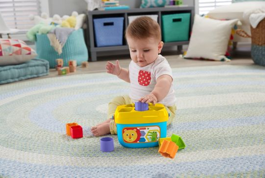 Baby playing with colorful blocks and sorting bucket lid from the toy First Blocks Sorting Bucket.