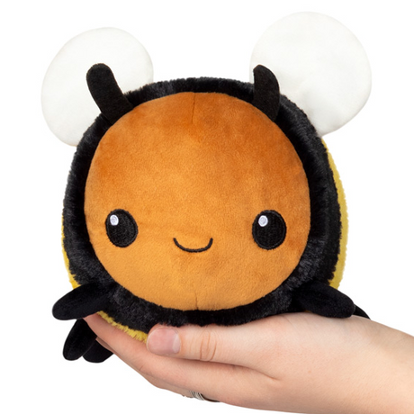 Hand holding a 6-inch soft plush bee toy with a smiling face, named Fuzzy Bumblebee Snackers.