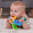 Baby chewing and exploring colorful Dimpl Clutch with sensory dimpl bubbles and silicone textures on a soft rug.