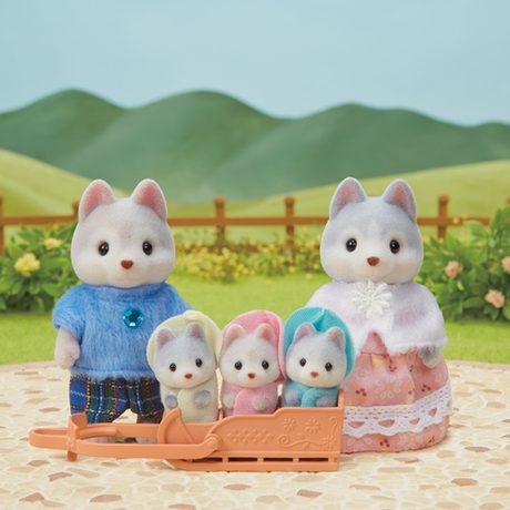 Calico Critters Husky Family with father, mother, and three triplets in hooded outfits riding a sled outdoors.