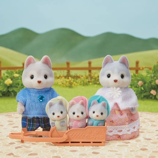 Calico Critters Husky Family with father, mother, and three triplets in hooded outfits riding a sled outdoors.