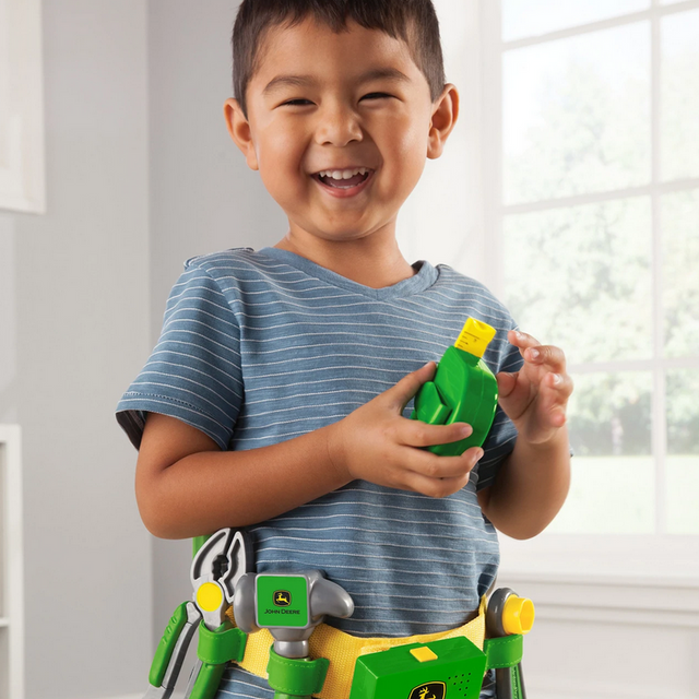 Child playing with the John Deere Talking Tool Set wearing the toolbelt with toy tools and electronic features.