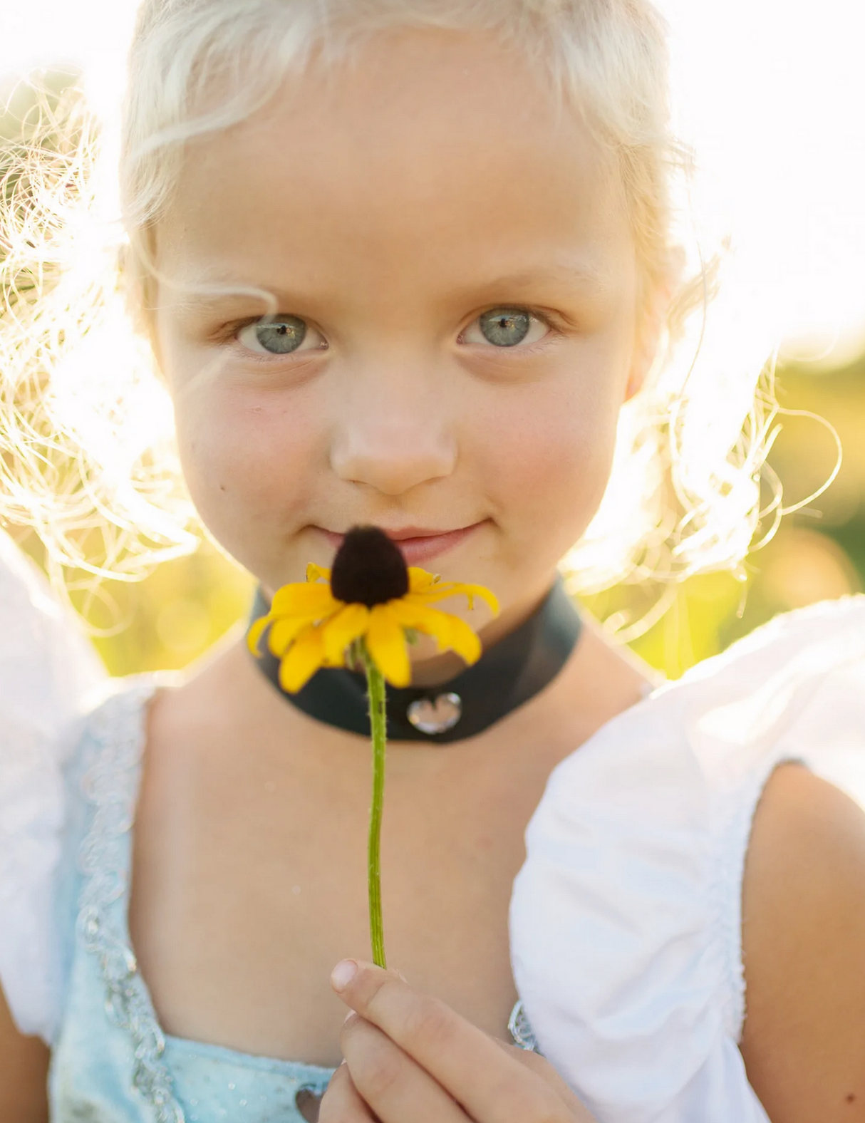 Deluxe Cinderella Gown Size 5-6 worn by a girl holding a yellow flower with sunlight highlighting her curls.