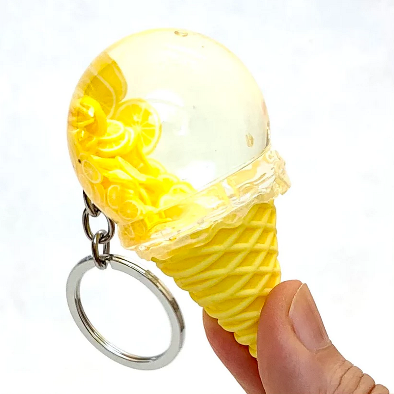 Hand holding a yellow Fruit Icecream Keychain with clear dome and lemon slice details on a white background.