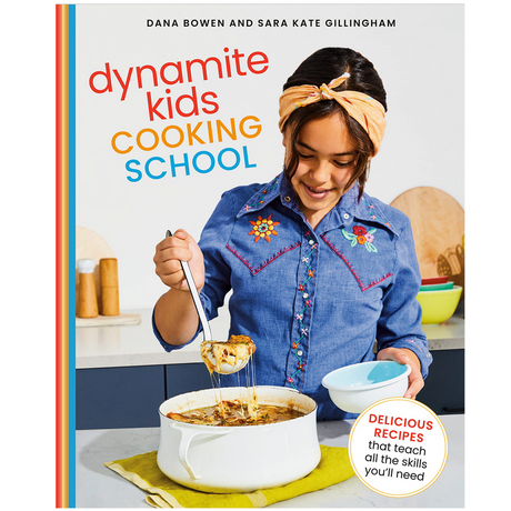 Dynamite Kids Cooking School cookbook cover with girl serving cheesy dish from white pot in modern kitchen.