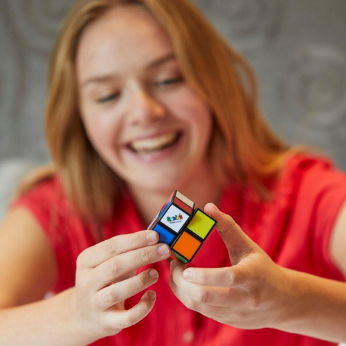 Smiling girl solving the Rubiks 2x2 cube, a compact brain teaser with smooth twists and vibrant colored tiles.