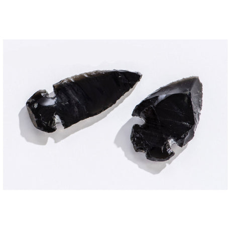 Two hand-crafted Arrowhead Obsidian pieces made from volcanic glass showing traditional carving details on white background