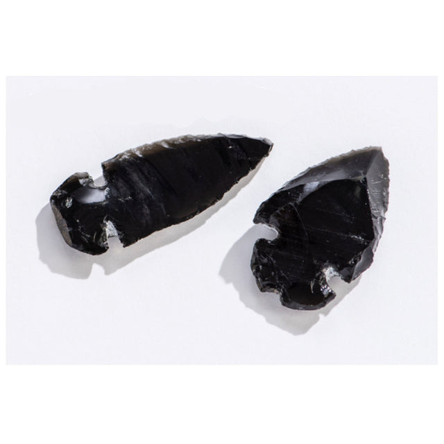 Two hand-crafted Arrowhead Obsidian pieces made from volcanic glass showing traditional carving details on white background
