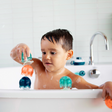 Child playing with colorful JELLIES Suction Cups stacked in the bathtub for creative bath time fun.