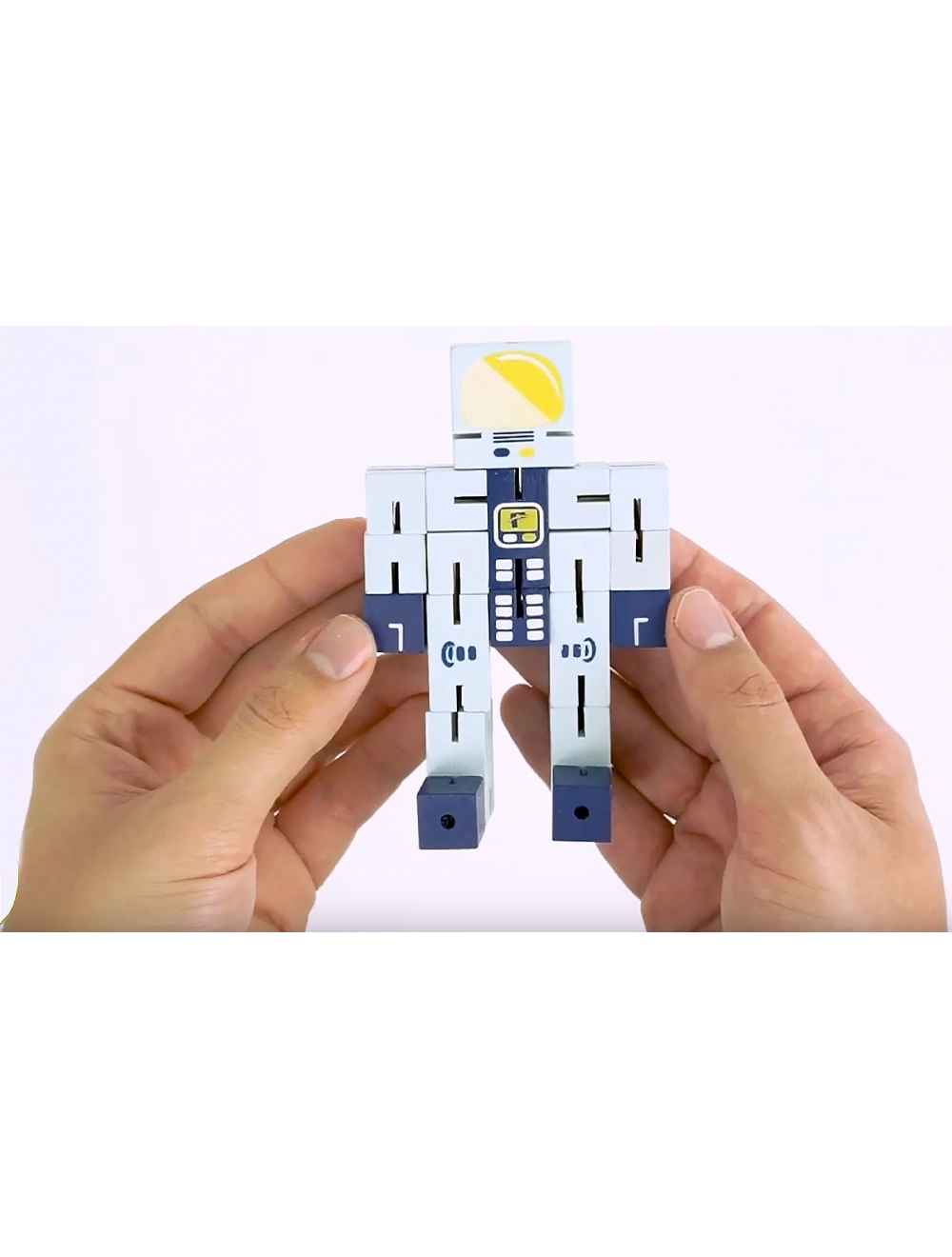 Hands holding the Puzzle Planet Astronaut wooden brainteaser puzzle in astronaut form with white and blue details.