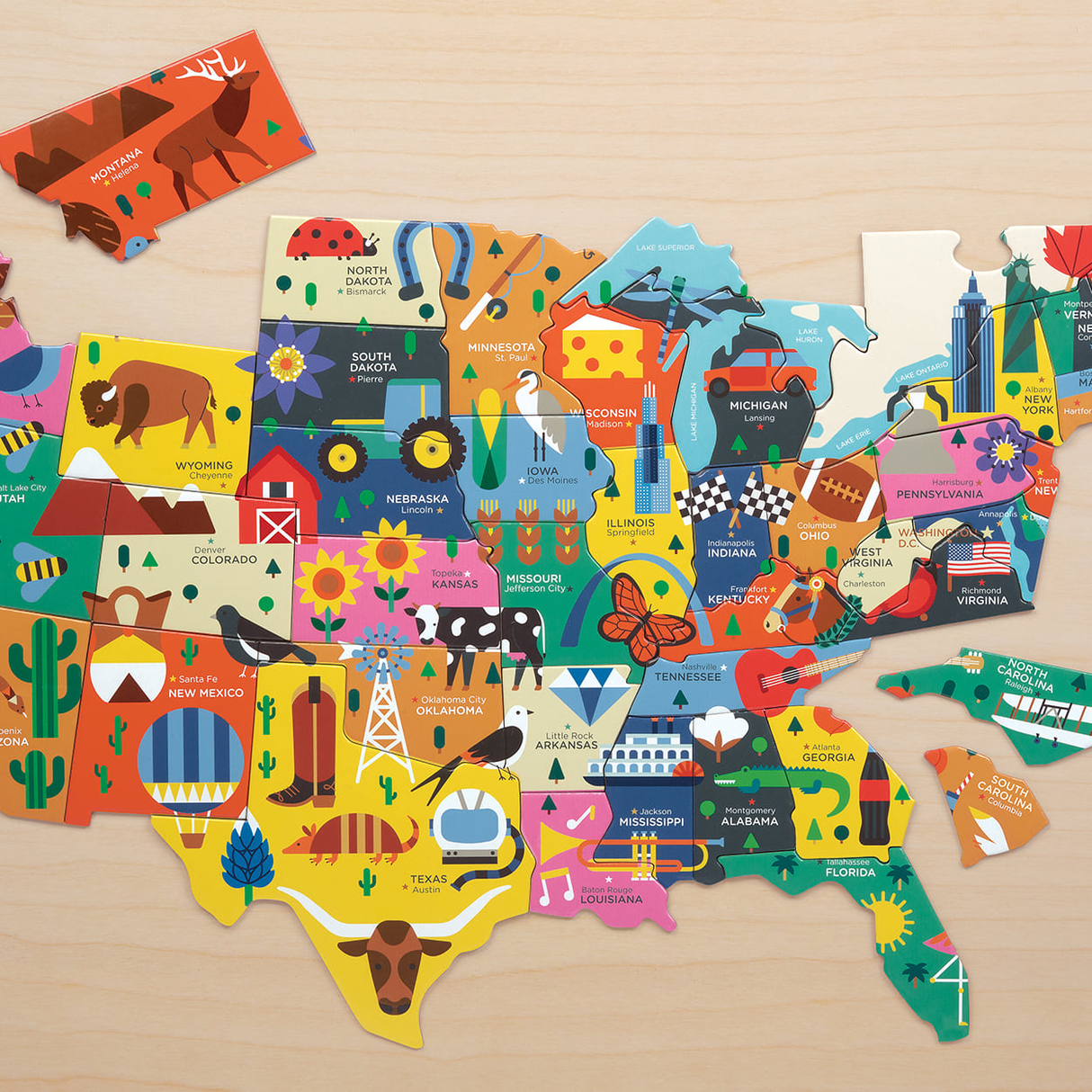 70pc USA Map Puzzle showing colorful state-shaped pieces with capital cities, nicknames, and fun illustrations for learning geography.