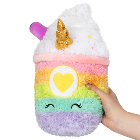 Hand holding Unicorn Latte Mini plush with rainbow stripes, golden horn, and heart detail, soft and cuddly toy.