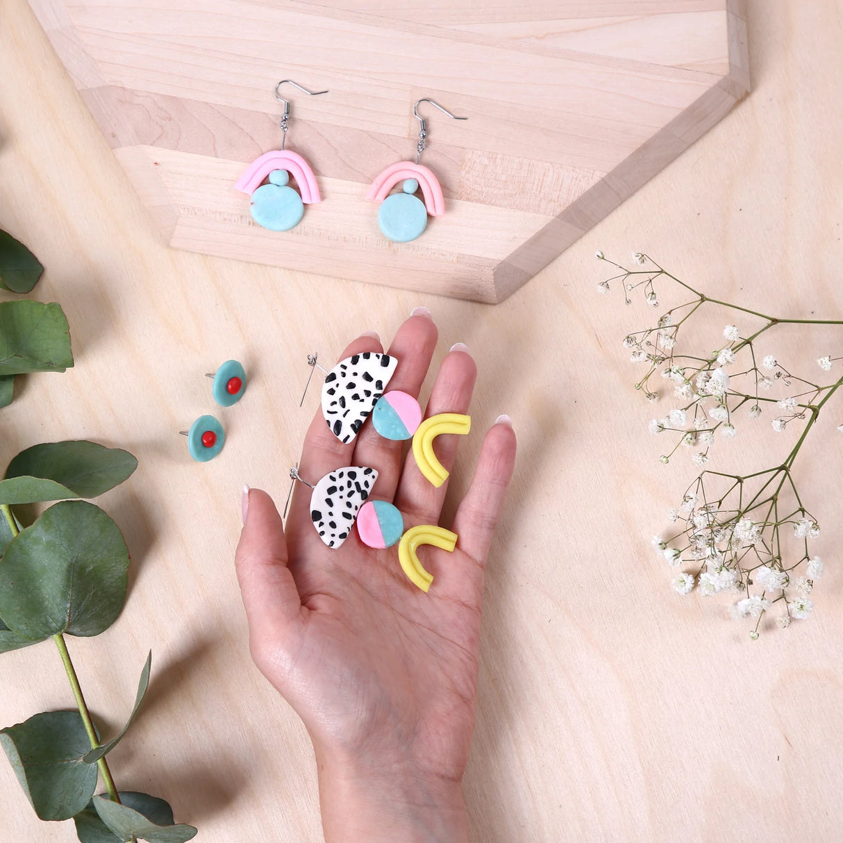 Crafters Polymer Clay Jewelry displaying colorful handmade clay earrings with floral decoration on wooden surface.