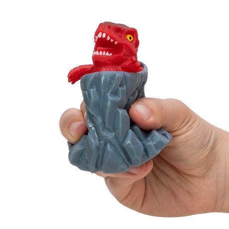 Hand squeezing the Volcanic Dino Poppers toy with a red T-Rex popping out of a gray volcano.