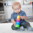 Baby playing with colorful Dimpl Stack stacking cups featuring textured silicone bubbles for tactile learning.