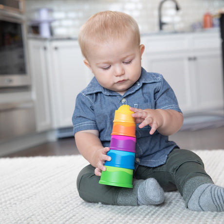 Baby playing with colorful Dimpl Stack stacking cups featuring textured silicone bubbles for tactile learning.