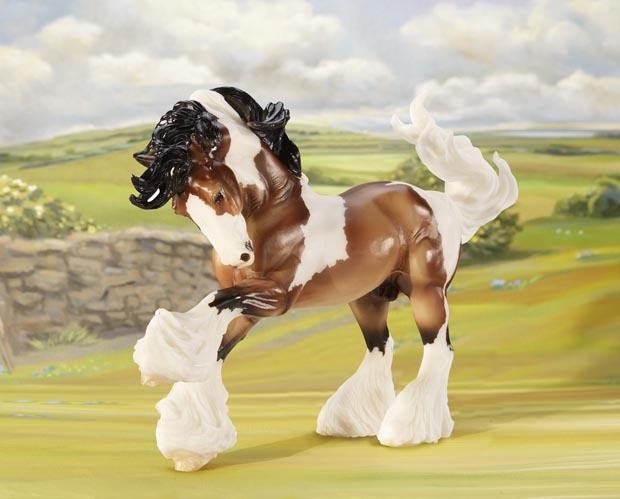 Gypsy Vanner model horse with lush mane, heavy leg feathering, and piebald coloring set against a countryside backdrop.