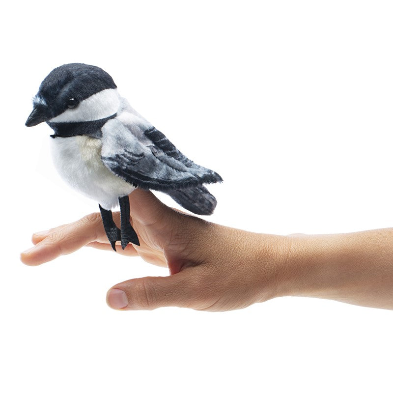 Chickadee Finger Puppet perched on a hand, featuring black, white, and yellow cozy printed fabric details.