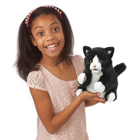 Girl holding a Kitten Tuxedo puppet with black and white fur, movable mouth, and cuddly design for playtime.