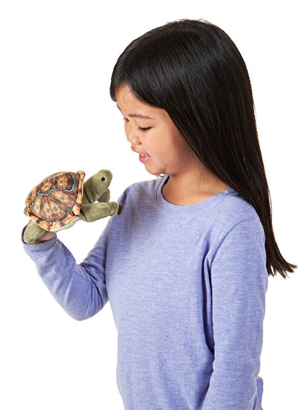 Child smiling and playing with a soft Mini Tortoise Finger Puppet that hides in its shell.