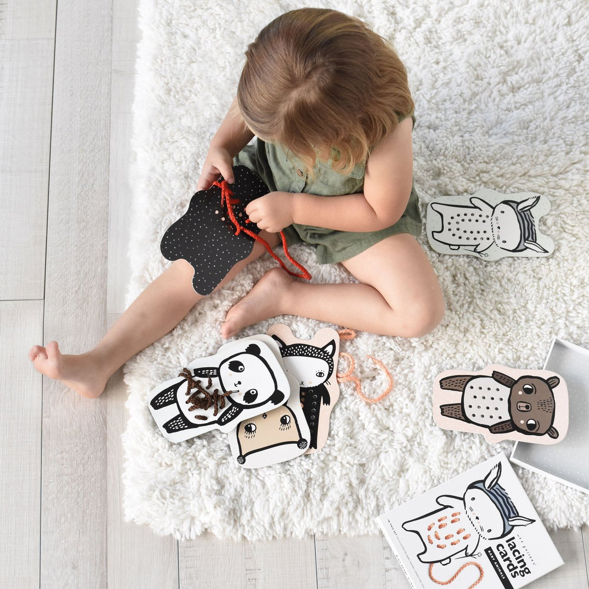 Child playing with Baby Animal Lacing Cards featuring hand-illustrated animals to develop motor skills and hand-eye coordination.