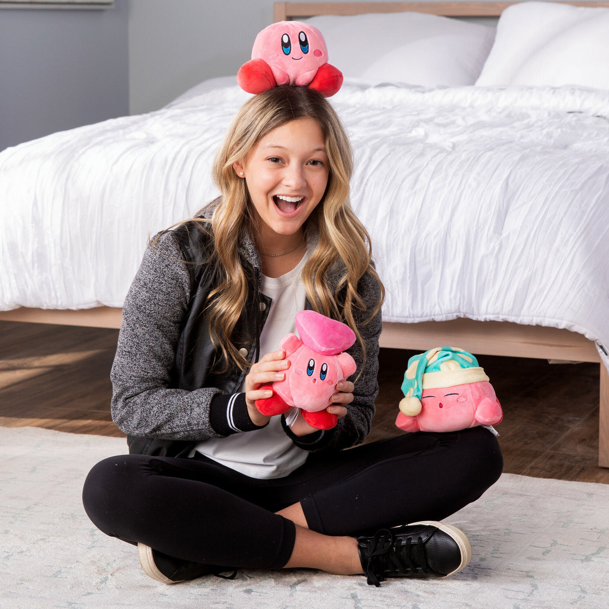 Kirby Character plush toys shown as soft, pink, squishy collectibles with a joyful woman holding and wearing them.