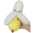 Hand holding a smiling plush toy of Banana Snackers partially peeled to show soft texture and friendly face.