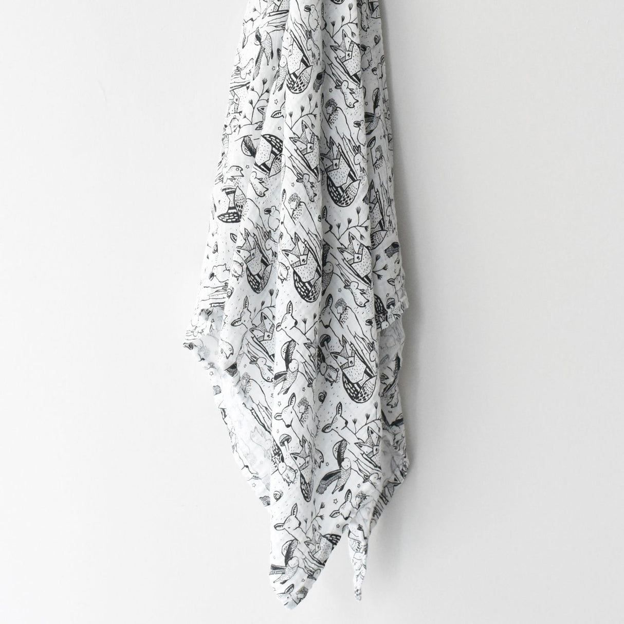 Organic Muslin Swaddle | Forest hanging, showing black and white forest animal pattern on soft organic cotton muslin fabric.