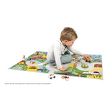 Child playing on Crossroads Countryside Play Mat featuring roads, farm, forest, animals, and buildings for imaginative play.