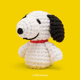 Crocheted Snoopy figure in white with black ears and red collar on bright yellow background