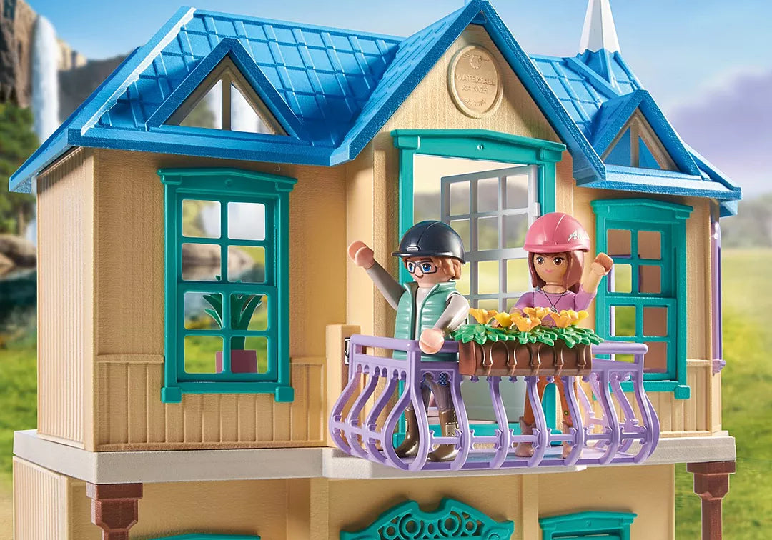 Horses of Waterfall | Waterfall Ranch featuring stable with two riders on balcony and scenic mountain background.