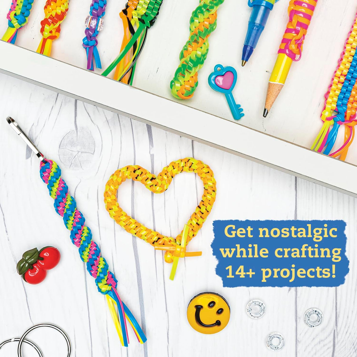 Lanyard Scoubidou & Boondoggle showing colorful braided keychains, charms, and crafting supplies on a white wood table.