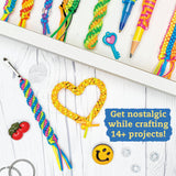 Lanyard Scoubidou & Boondoggle showing colorful braided keychains, charms, and crafting supplies on a white wood table.