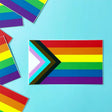 Progress Pride Flag Sticker showing vibrant colors and chevron design on a 3" x 1.8" vinyl sticker for laptops or bottles.