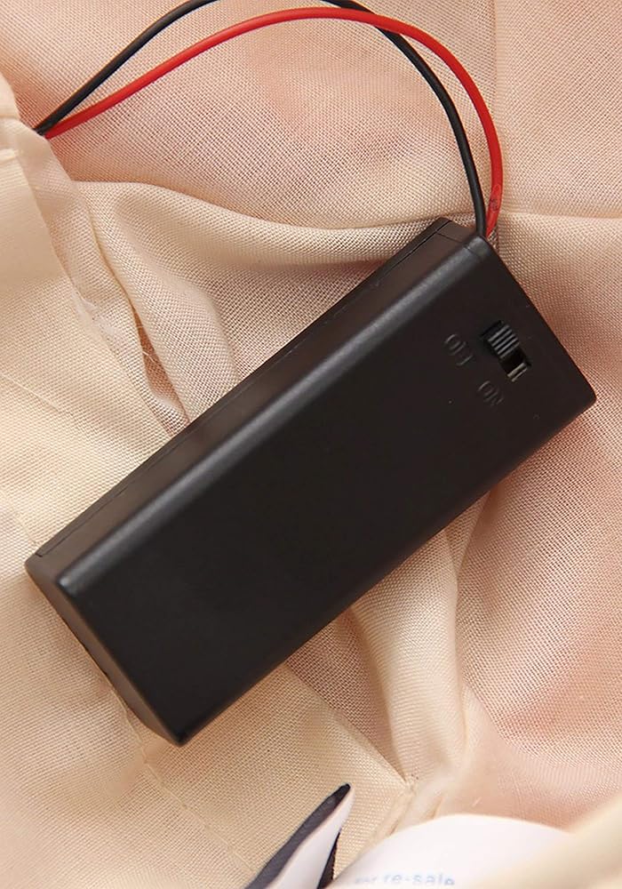 Battery pack with on/off switch for the Yeti Soft Hat shown on beige fabric background.