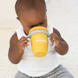 Baby holding yellow Happy Sippy Cup | Hello Sunshine with dual handles and spill-proof lid.
