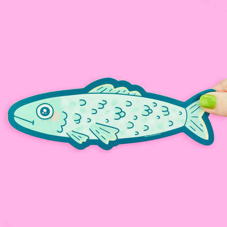Hand holding a blue and teal Sardine Fish Long Sticker on a pink background with a friendly design.
