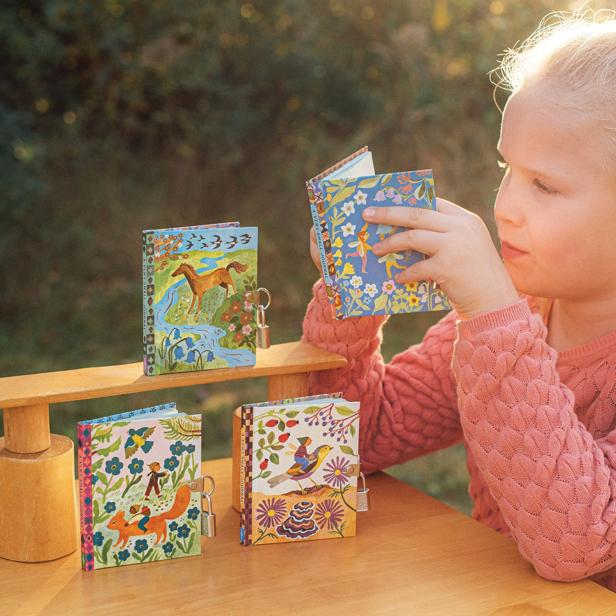 Very Small Journal | Gemma pocket-sized journals with fairy illustrations, metal locks, and sustainable materials on wooden table.
