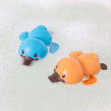 Two bath racer platypuses sitting in soapy bath water- one is orange, the other is blue.