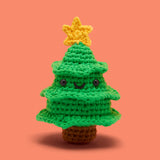 Crocheted green Christmas tree with smiling face and yellow star on top on an orange background