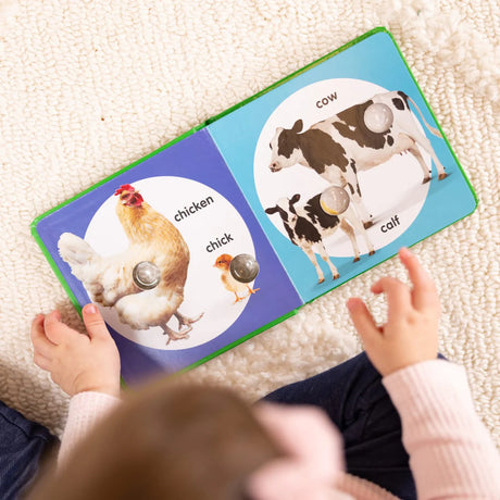 Child playing with Poke A Dot! Farm Animal Families interactive board book featuring farm animals and babies.