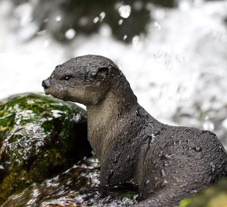 River Otter figurine perched on a mossy rock with water droplets, showcasing detailed semiaquatic mammal features.